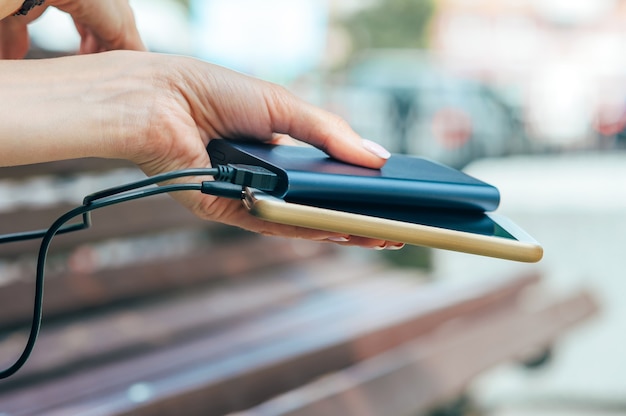 Foto powerbank in der hand des mädchens. vor dem hintergrund der stadt.