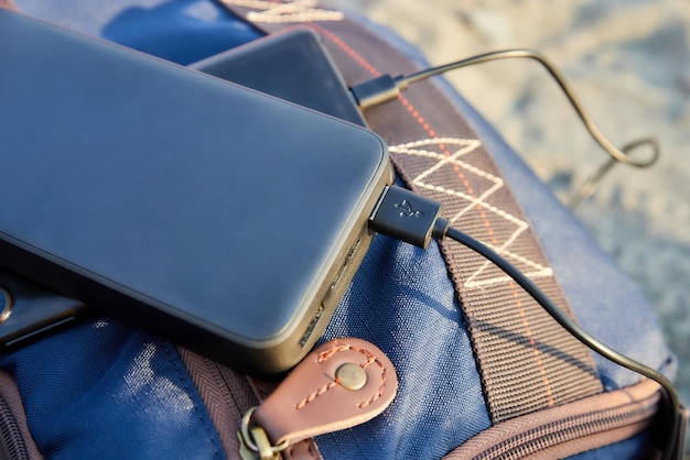 Powerbank lädt das Handy am Strand am Touristenrucksack auf