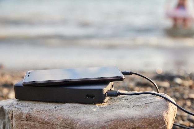 Powerbank lädt das Telefon am Strand am Meer auf