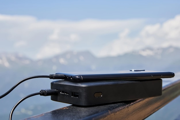 Powerbank lädt das Telefon auf dem Hintergrund der Berge auf