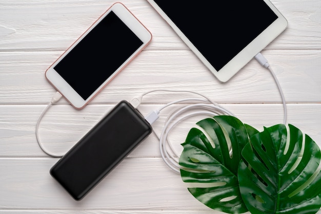 Powerbank lädt Smartphone und Tablet auf weißem Hintergrund