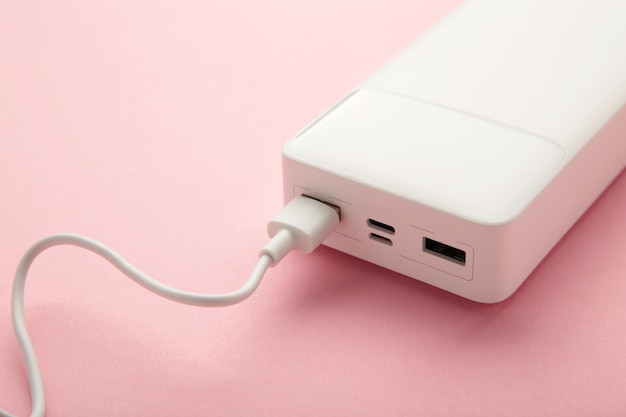 Powerbank portátil con cable usb sobre fondo rosa