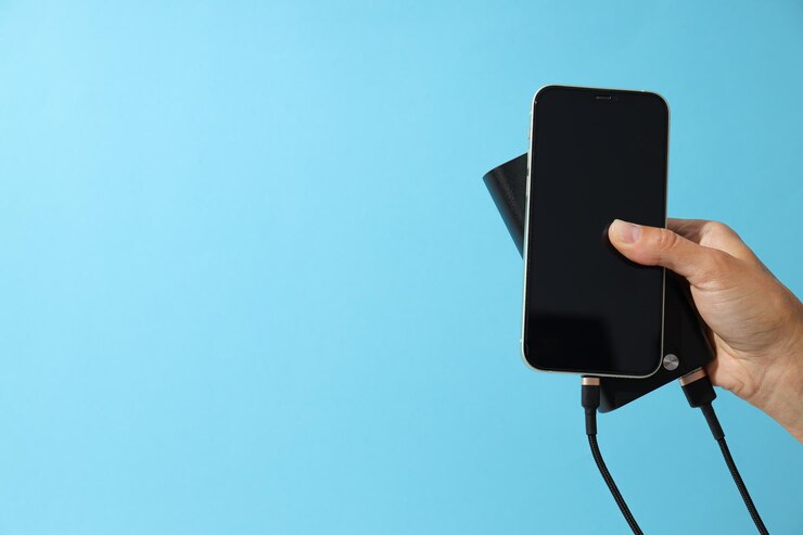Powerbank y teléfono inteligente en mano sobre fondo azul espacio para texto