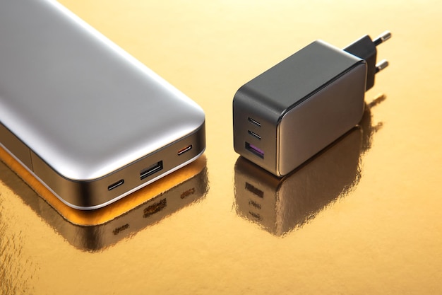 Powerbank und Ladestecker auf goldenem Hintergrund Elektronische Geräte zum Aufladen von Geräten