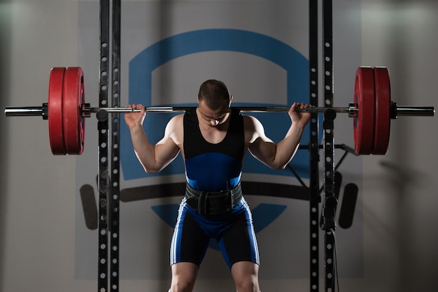 Foto powerlifter con barra ejercitando las piernas dentro del gimnasio