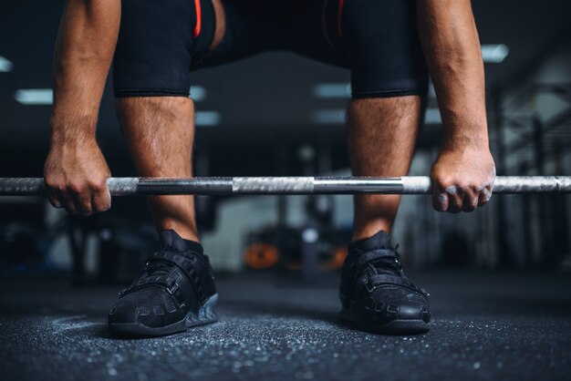 Powerlifter se prepara para levantamento terra com barra na academia