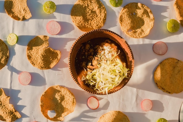 Pozole de frango acompanhado de orégano alface cebola rabanete limão chili e torradas