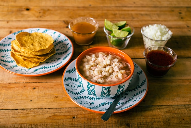 Pozole servido em prato fundo com tostadas e legumes em mesa de madeira Comida típica mexicana