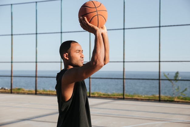 Pportrait de un joven deportista concentrado jugando baloncesto