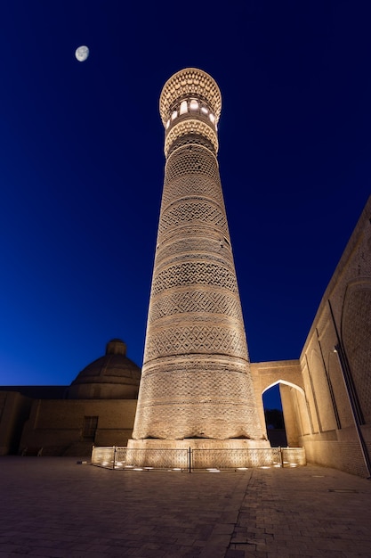 Praça PoiKalyan à noite com minarete Kalyan brilhantemente iluminado Bukhara Uzbequistão
