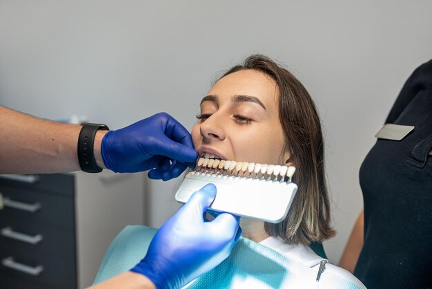 En la práctica profesional, el dentista verifica el nivel de blanqueamiento de los dientes del paciente tiñéndolos del médico Concepto dentistas cuidado de la salud perfección blanca