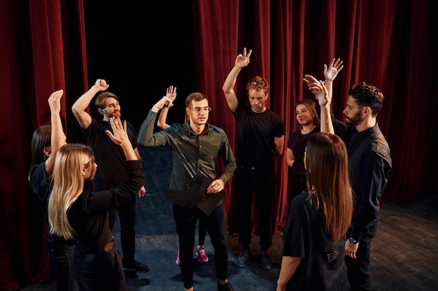 Práctica en progreso Grupo de actores con ropa de color oscuro ensayando en el teatro