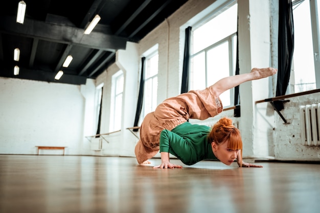 Práctica de yoga. Instructor de yoga profesional con cabello rojo mirando concentrado mientras hace hatha yoga