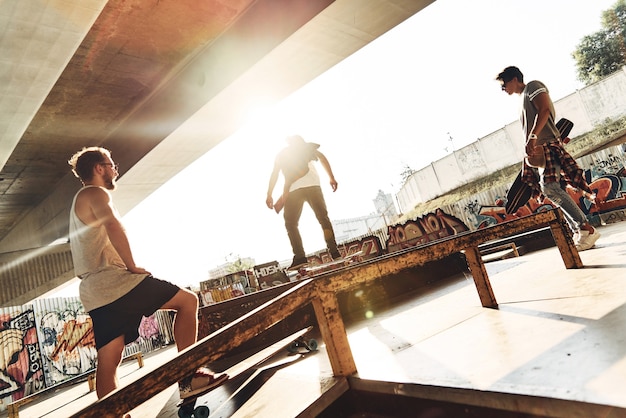 Practicando sus trucos. Grupo de jóvenes en patineta mientras pasan el rato en el parque de patinaje al aire libre