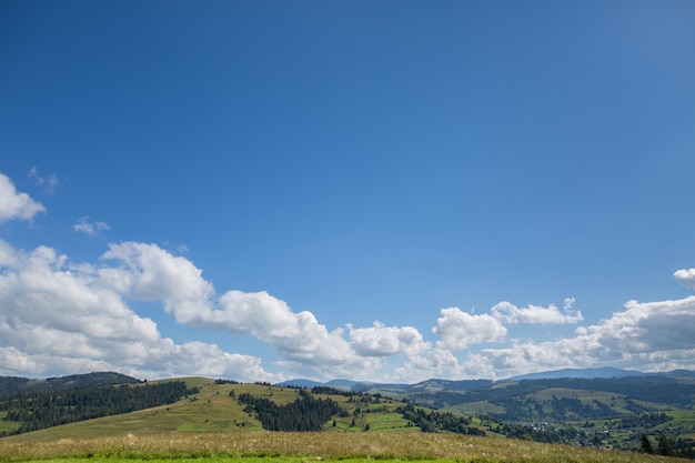 Prado, montanha e céu azul com nuvens