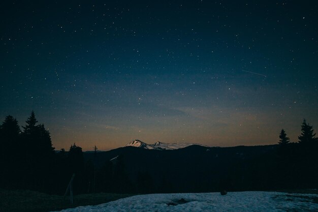 Prado nevado montañas nevadas y estrellas en el fondo