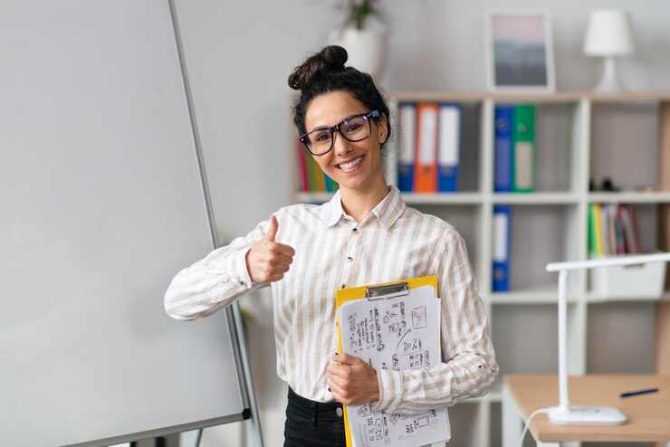 Foto präsentationskonzept glückliche büroangestellte in der nähe eines leeren leeren whiteboards mit daumen nach oben und
