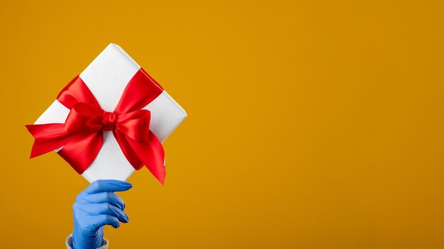 Präsentieren Sie eine Überraschungs-Covid-Urlaubs-Valentinstag-Grußhand in Schutzhandschuhen, die eine Geschenkbox halten