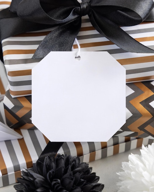 Präsentieren Sie mit leerem Geschenkanhänger und schwarzer Schleife Nahaufnahme Geschenkboxen verpackt in gestreiftem und Chevron-geometrischem Papier in der Nähe von Schwarz-Weiß-Dekor Weihnachten Neujahr Geburtstag Jubiläum Etikettenmodell