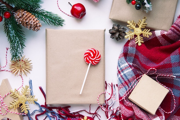 Foto präsentiert in braunem bastelpapier, schachteln, süßigkeiten, plaid und weihnachtsdekoration auf dem tisch. speicherplatz kopieren. umweltfreundliches neujahrskonzept