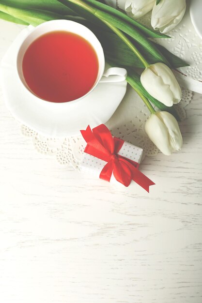 Präsentkarton mit Tulpen und Tasse Tee auf Draufsicht des Holztischs