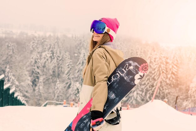 Foto praga checa diciembre chica feliz snowboarder posando con gafas de sol con snowboard