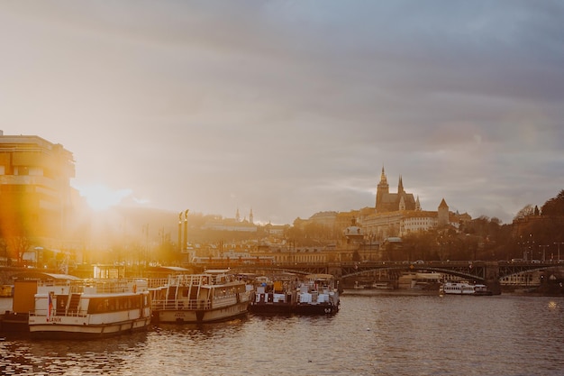 Praga durante a foto do crepúsculo da noite com vista para a Ponte Carlos de um navio navegando no rio Vltava