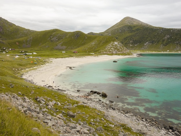 Praia azul turquesa e montanhas ao fundo Noruega