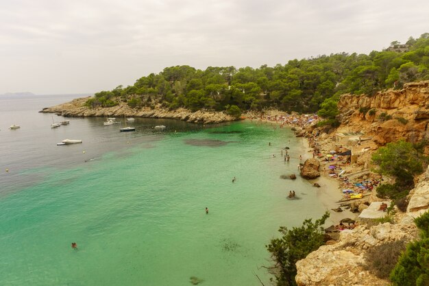 Praia Benirras, Ibiza, Espanha - 27 de agosto de 2017: Jovens pulando dentro do oceano no dia de excursão de verão - Férias, juventude e conceito divertido - Foco suave no homem esquerdo - Distorção da lente olho de peixe