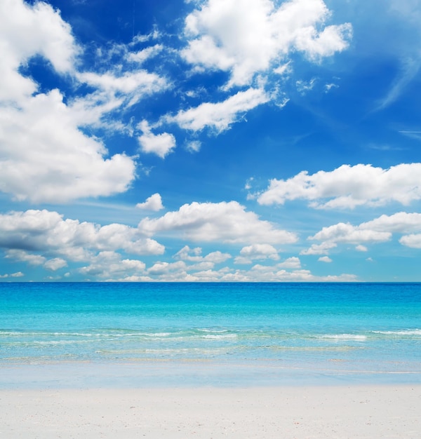 Praia branca e água azul em um dia nublado
