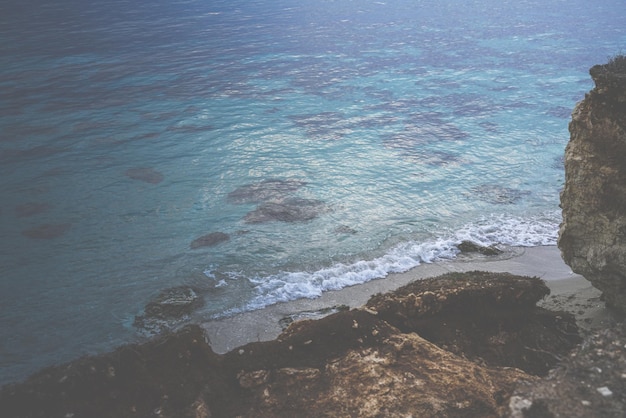 Praia com areia e rochas com frente para o mar cristalino no Mediterrâneo