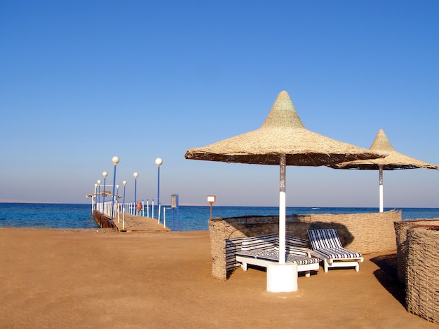 Praia com guarda-sóis, espreguiçadeiras e um píer na costa do Egito.