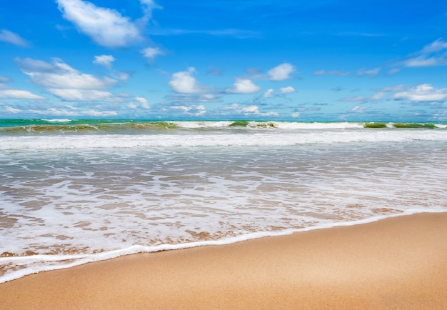 Praia com mar azul e areia branca no céu azul