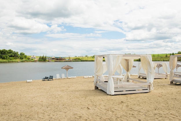 Praia com pavilhões, lago, nuvem, céu