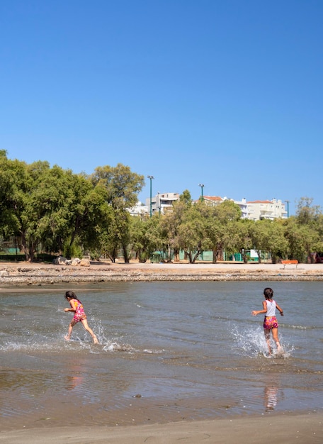 Praia da cidade e crianças brincando no mar na Grécia