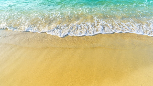Praia de areia à beira-mar com espuma branca