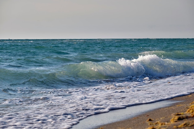 Praia de areia à beira-mar com ondas espumosas esmagando na costa