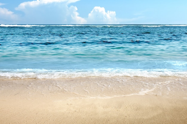 Praia de areia com o oceano azul e o fundo do céu azul
