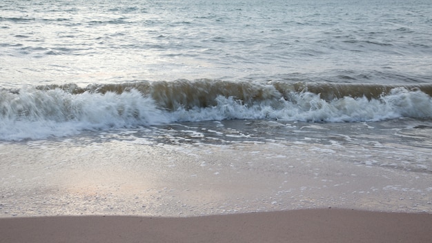 Praia de areia com ondas do mar por do sol.