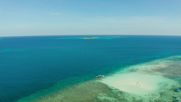 Praia de areia com turistas em um atol de coral em águas turquesa acima de balabac