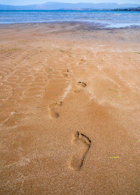 Praia de areia e pegadas na areia na maré baixa na praia de liani ammos em halkida grécia