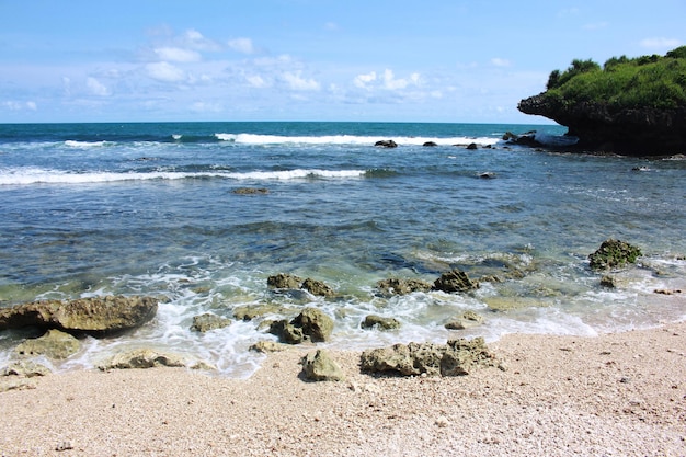 Praia de coral de areia branca com água do mar azul clara, Krakal Beach Indonésia