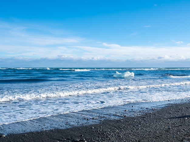 Praia de diamante de areia negra com montanhas de ondas e neve na Islândia