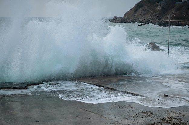 Praia de pedra do mar turquesa, quebrando ondas em um dia nublado de primavera. Belo fundo do mar.