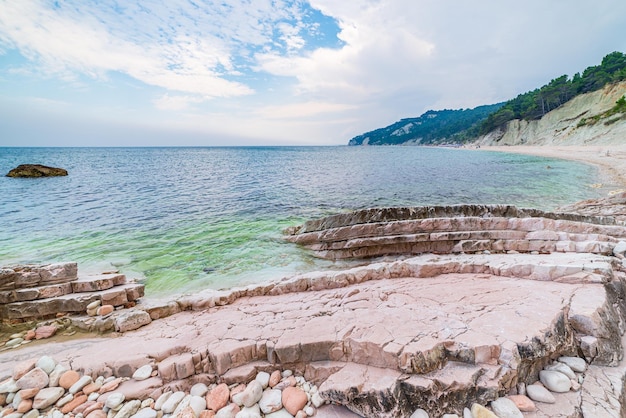 Praia de seixos baía colorida no parque natural de Conero dramática costa promontório rocha penhasco mar adriático destino turístico Itália turquesa águas transparentes