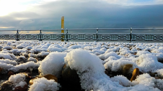 Praia de seixos coberta de neve ao nascer do sol em uma manhã gelada de invernos congelados