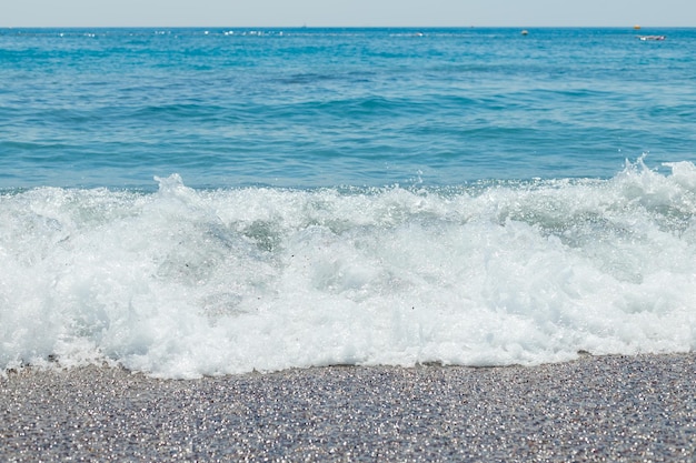 Praia de seixos com fundo de textura de água do mar azul Água do mar clara em uma praia de seixos água pura no litoral de pedra com litoral apedrejadomaravilhosa paisagem de férias para o paraíso de verão