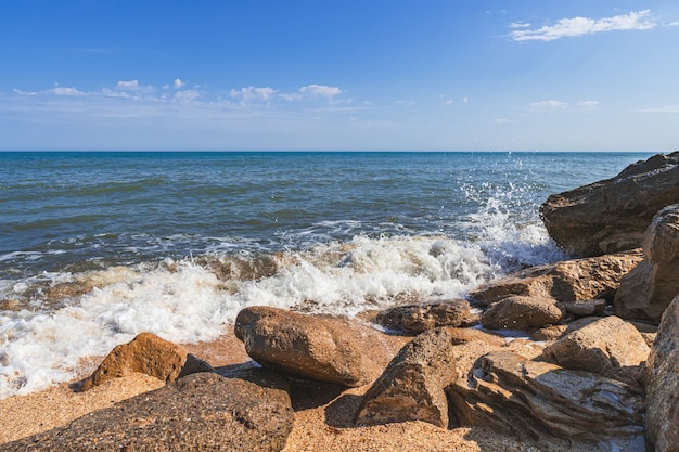 Praia de verão com pedras e ondas fortes