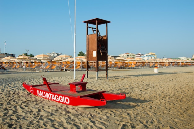 Praia de viagem romagna praia e mar em rimini com barco de resgate vermelho e guarda-chuvas laranja