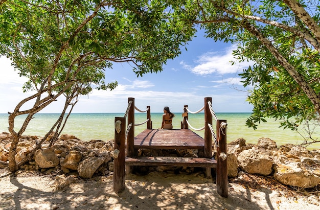 Praia do Caribe com água verde e palmeiras e uma mulher olhando para a água em Cancun, México